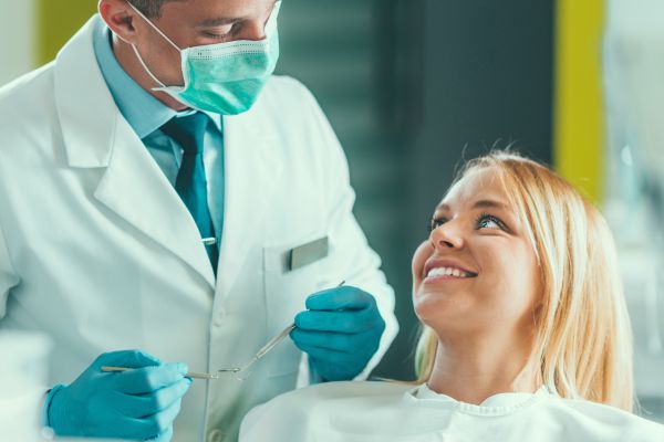 Dentist talking to patient. Patients is sitting in the treatment chair.