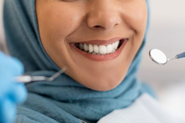 close up photo of a woman smiling. There is a dental mirror held near her mouth